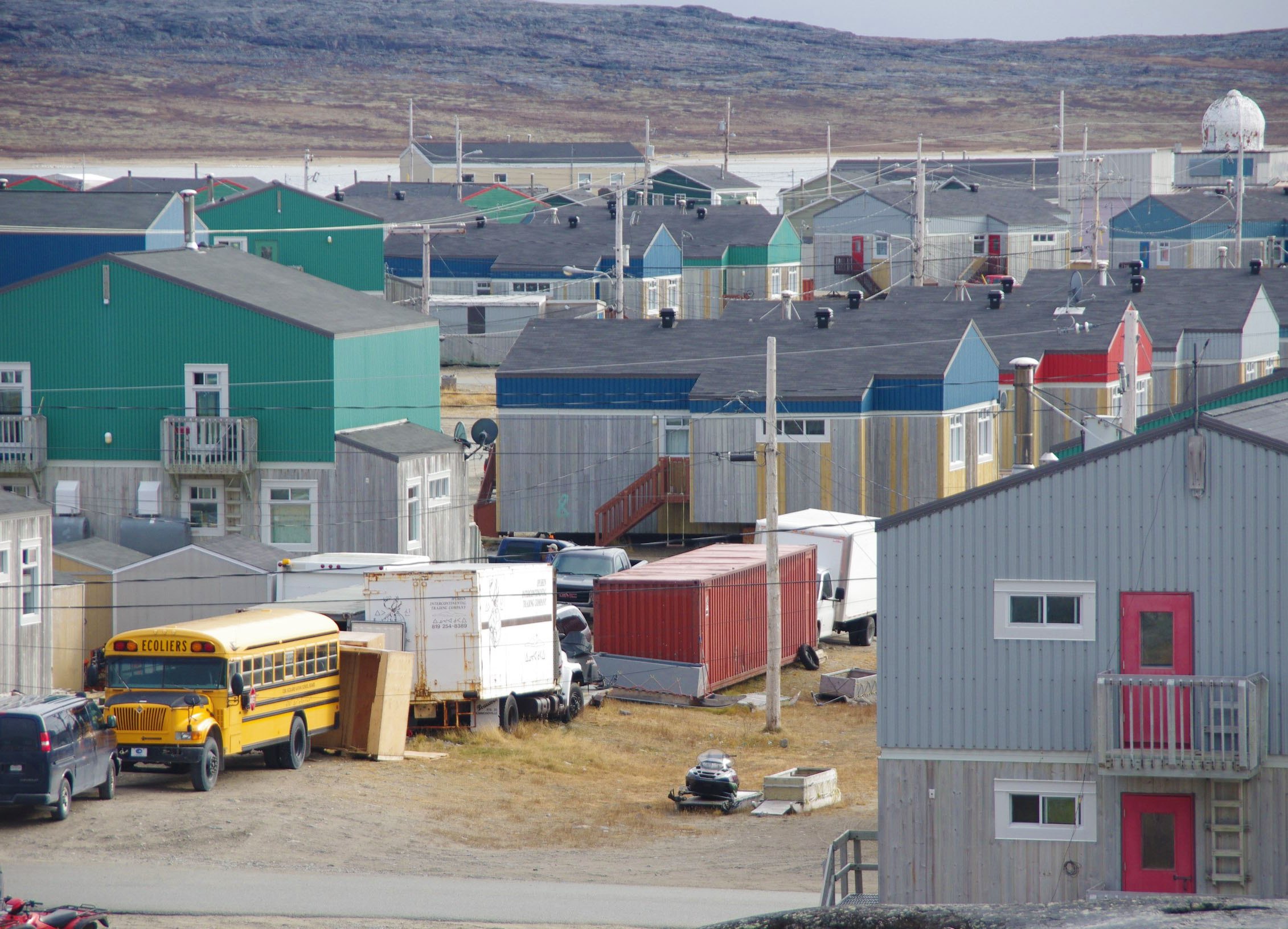 Northern Quebec community: colourful houses, a school bus and rocky hills in the background